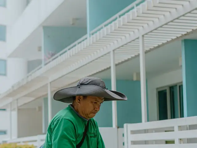 Landscaper trimming a hedge outside a home